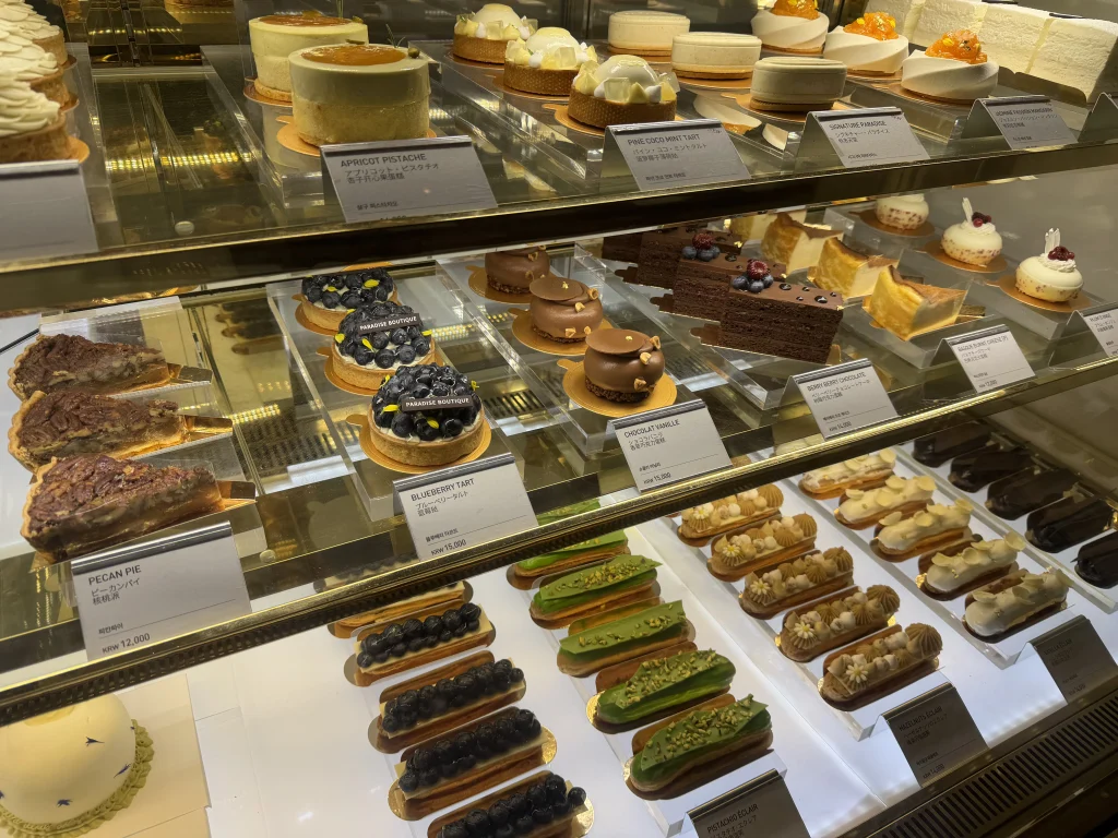 パラダイスシティのガーデンカフェに並ぶブルーベリータルト、チョコレートケーキ、エクレアなどのスイーツ