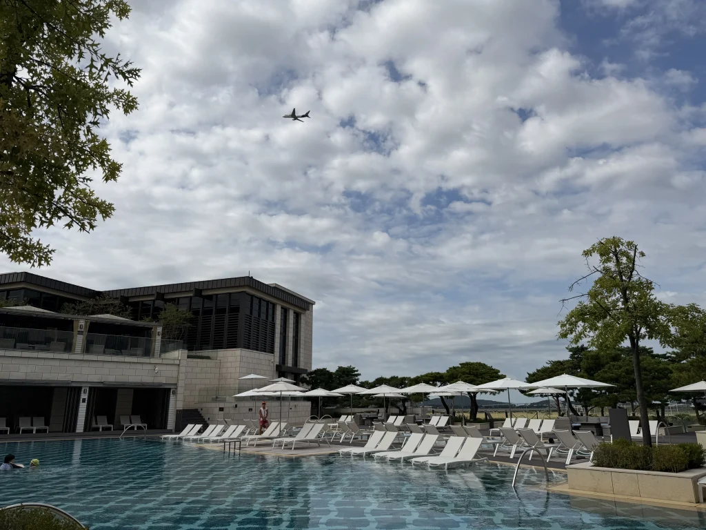パラダイスシティホテルの屋外プールと上空を通過する飛行機