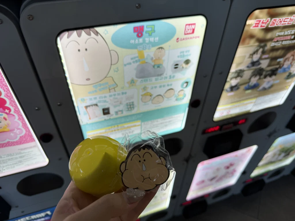 パラダイスシティPLAZAのガチャガチャで入手したキャラクターグッズ(クレヨンしんちゃんのボーちゃん)と黄色いカプセル