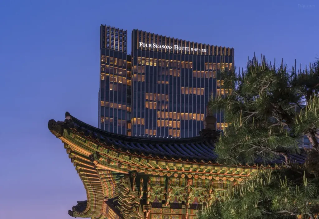 フォーシーズンズホテルソウルの夕暮れの外観。ライトアップされた高層ホテルと韓国の伝統建築が調和するソウルの美しい景観。