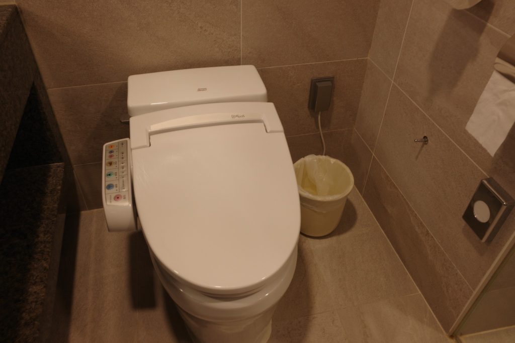 ソルビーチ三陟の温水洗浄便座付きトイレとベージュ色のタイル壁