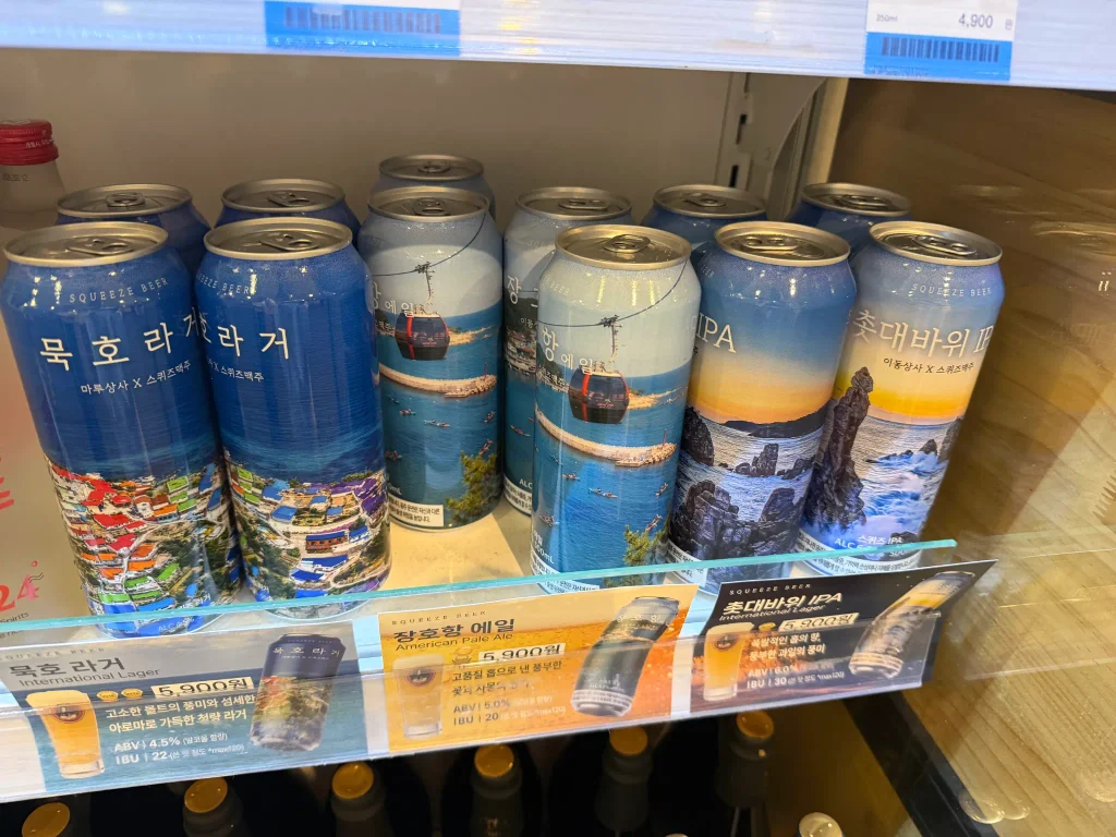 ソルビーチ三陟の冷蔵棚に並ぶ束草の地名や風景が描かれた缶ビール