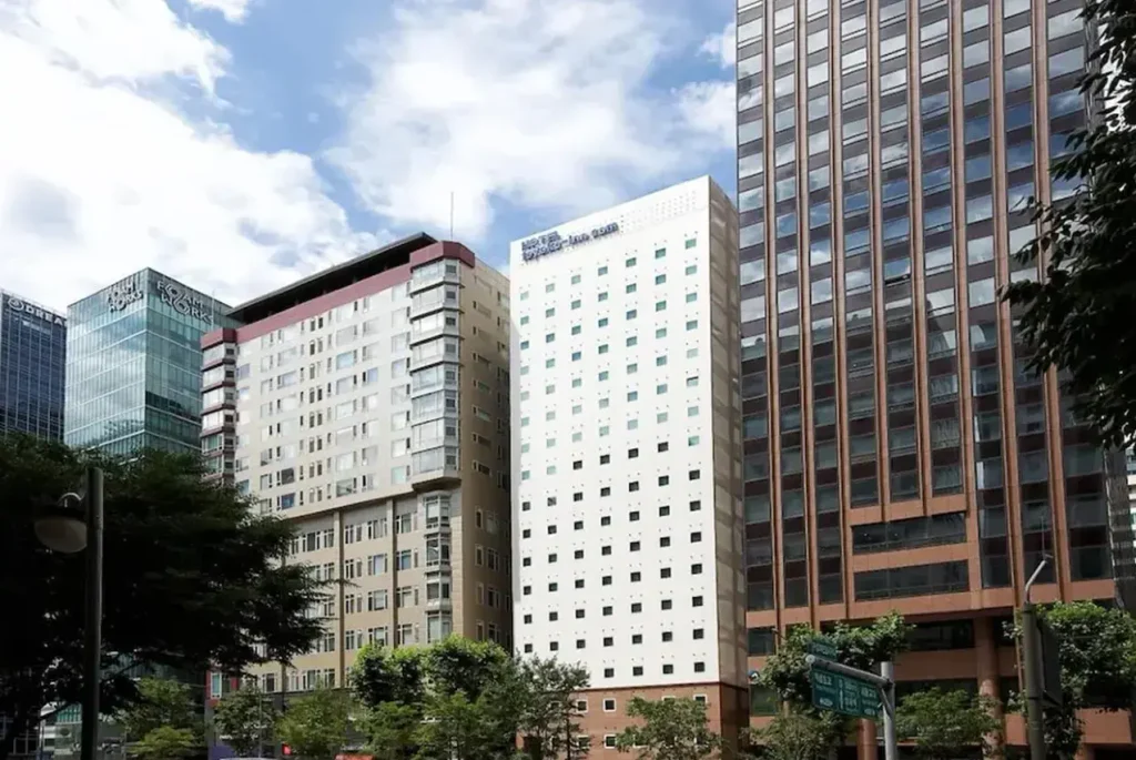 東横INNソウル江南のホテル外観。ソウル・江南の高層ビル街に位置し、白い壁面に客室の窓が規則的に並ぶホテルの建物。